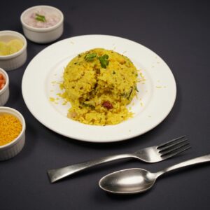 A vibrant serving of Indian poha accompanied by fresh sides, perfect for breakfast.